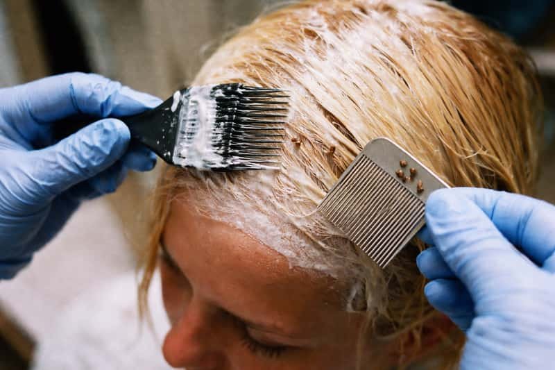Close-up of blonde highlighted hair strands against dark Close-up of blonde highlighted hair strands against dark background, showing bleached sections with visible texture and damag